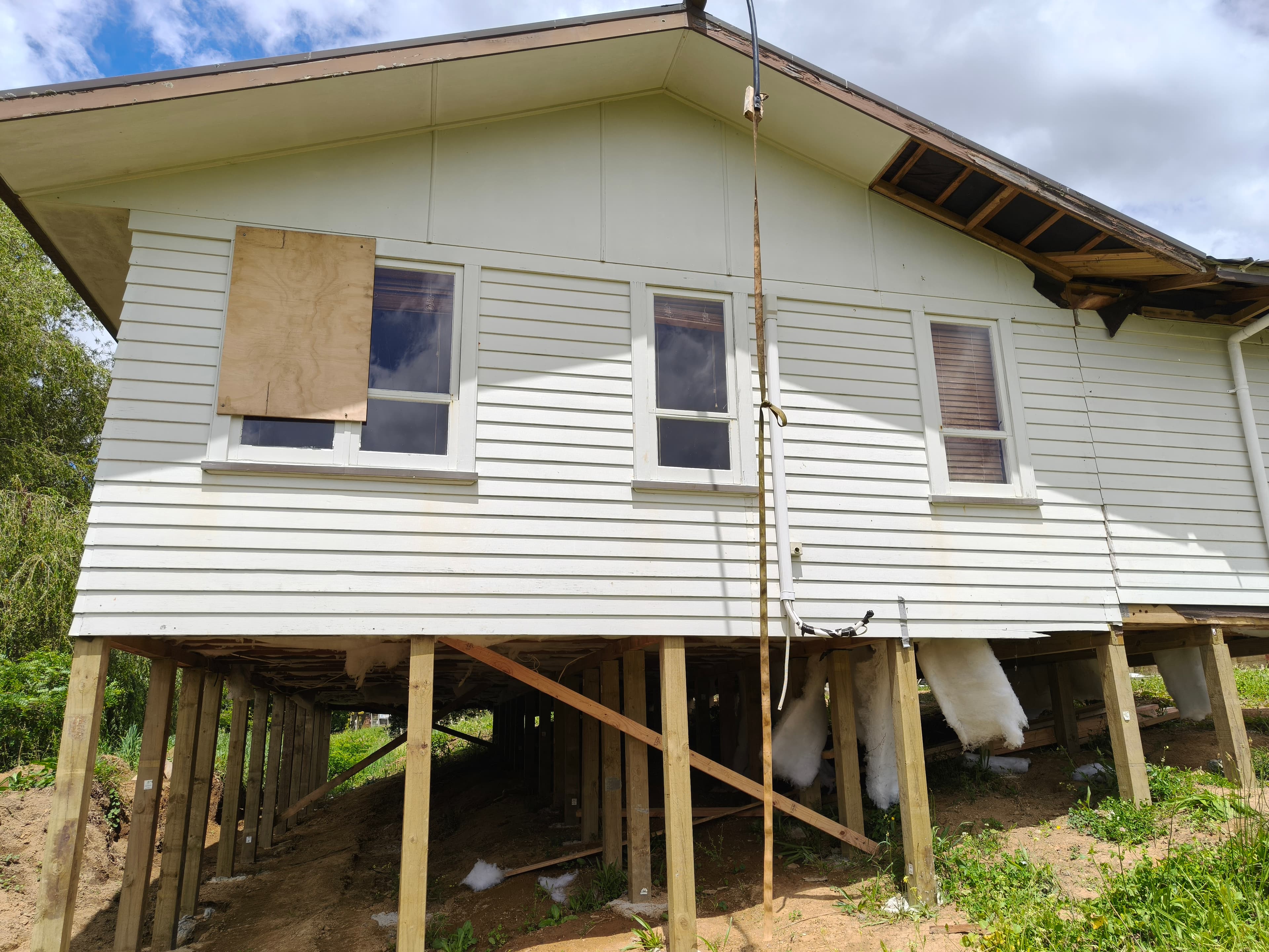 Relocatable house on tall and short timber piles following a sloping building platform.
