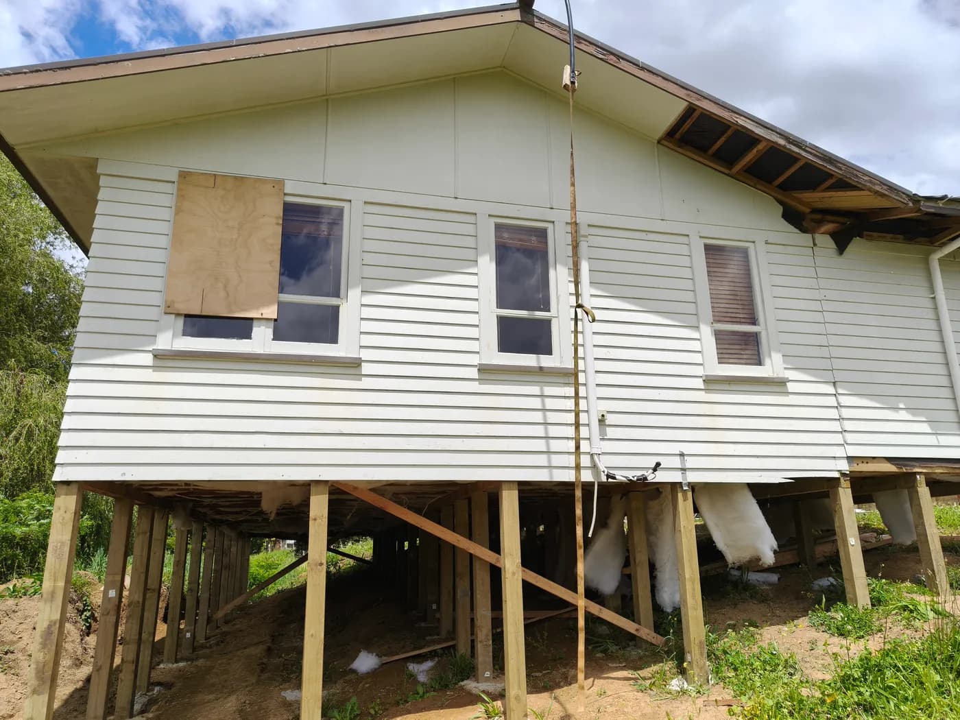 Relocatable house on tall and short timber piles following a sloping building platform.