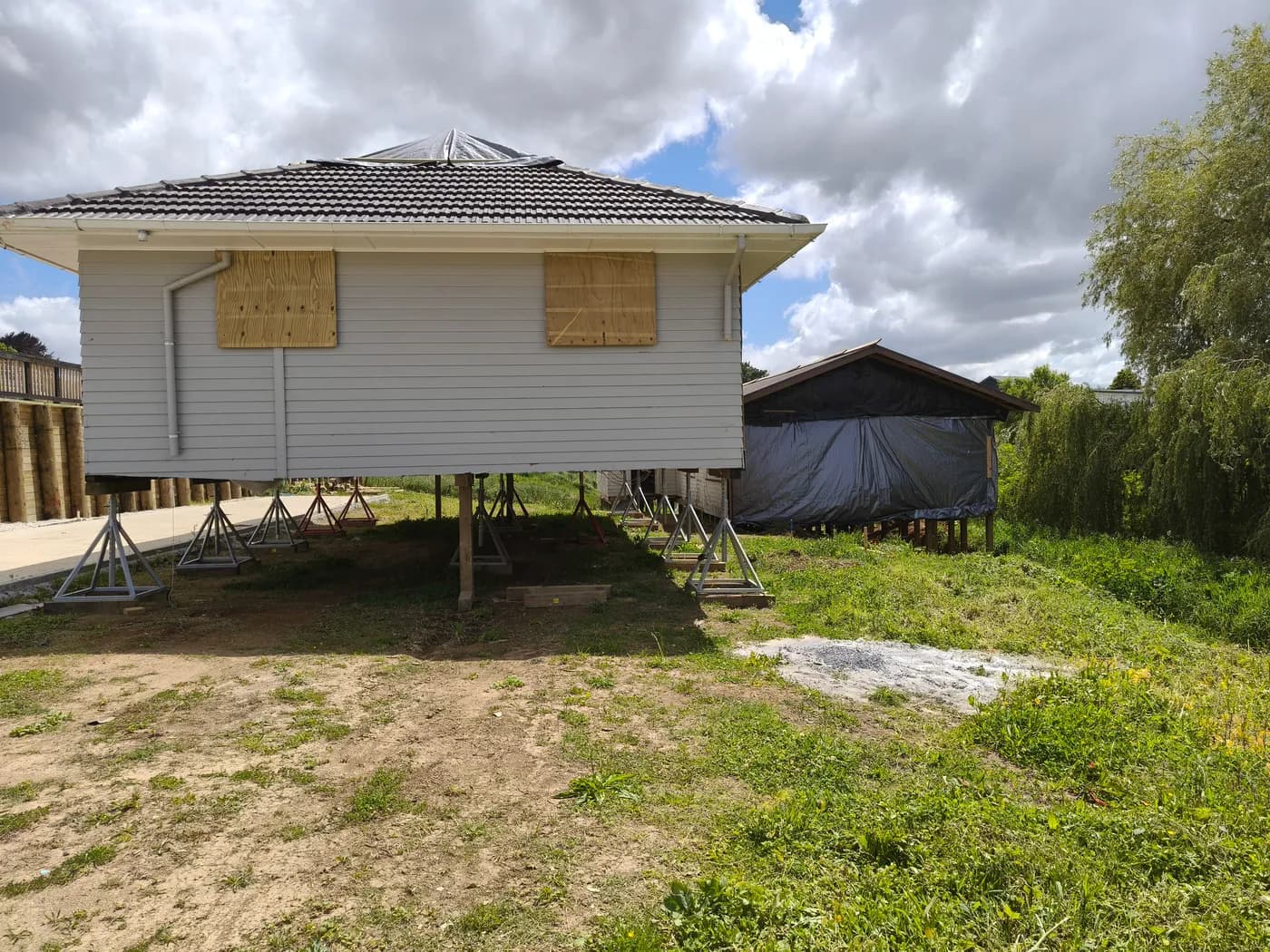 Relocatable dwelling raised on temporary screw jacks and steel stands on a new site before permanent foundations are completed.